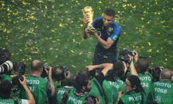 Kylian Mbappé brandit fièrement le trophée de la Coupe du monde, devant une meute de photographes, le 15 juillet 2018 à Moscou 