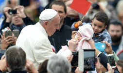 Le pape François salue un bébé pendant l'audience générale au Vatican le 18 novembre 2015