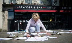 Une femme étale des dizaines de blouses blanches, toques et plateaux sur une place face à un restaurant à Nantes, ouest, le 27 mai 2020, pour protester contre les conséquences du confinement
