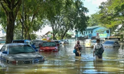Des gens pataugent dans l'eau près de voitures partiellement submergées à Shah Alam en Malaisie le 21 décembre 2021