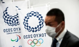 Un homme porte un masque à côté des logos des Jeux olympiques et paralympiques de Tokyo-2020 le 11 mars 2020 à Tokyo (Japon)