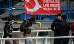 Un policier escorte un des migrants renvoyés par ferry depuis la Grèce jusqu'au port turc de Dikili, le 8 avril 2016