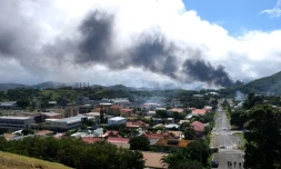 Un panache de fumée est visible au loin, alors que des émeutes ont lieu en Nouvelle-Calédonie en écho à une révision constitutionnelle examinée à l'Assemblée nationale, le 14 mai 2024 à Nouméa en Nouvelle-Calédonie