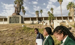 Des jeunes filles en uniforme scolaire passent devant le mémorial aux victimes du génocide commis par les colons allemands en 1904 contre les Hereros et le Namas en Namibie à Windhoek, le 20 juin 2017