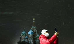 Une femme masquée prend une photo sur la place Rouge à Moscou, le 26 novembre 2020