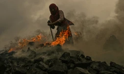 Une jeune femme récupÚre du charbon au milieu des flammes dans une mine de charbon à ciel ouvert, à la périphérie de Dhanbad, le 6 juillet 2023 en Inde