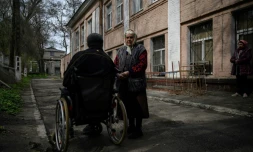 Une femme ùgée à cÎté d'un homme en fauteuil roulant, à Dnipro, le 16 avril 2022