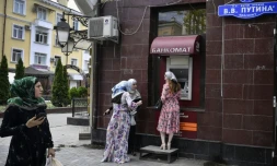 Des femmes se tiennent devant un distributeur de billets situé sur l'avenue Vladimir Poutine à Grozny, en Tchétchénie, le 26 juillet 2019
