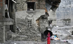 Une femme marche au milieu des ruines laissées par des crues soudaines dans le district de Nuwakot, au Népal, le 1er septembre 2026