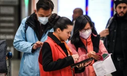 Une employée aide des voyageurs en provenance de Chine le 26 janvier 2020 à l'aéroport de Roissy 