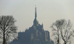 Un hélicoptÚre hélitreuille la statue de l'archange qui domine l'abbaye du Mont Saint-Michel, le 15 mars 2016