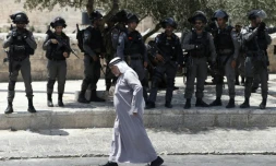 Un Palestinien marche devant la police israélienne à l'extérieur de la vieille ville de Jérusalem le 28 juillet 2017