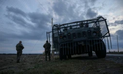 Des soldats ukrainiens devant un véhicule militaire blindé entouré d'une cage de protection contre les attaques de drones, sur une route près d'Oleksandrivka, le 6 octobre 2025