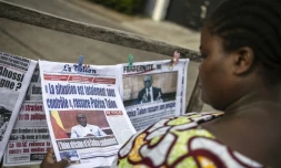 Une cliente regarde les titres des journaux devant un kiosque à Cotonou (Bénin), le 8 décembre 2025