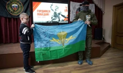 Anatoli, ex-paramilitaire russe de Wagner de retour du front ukrainien, offre à l'écolier Ivan un drapeau signé par d'anciens combattants du PMC Wagner, en récompense pour les dessins, messages et cadeaux qu'il a envoyés aux soldats russes, le 24 janvier 2025 à Istra, au nord-ouest de Moscou