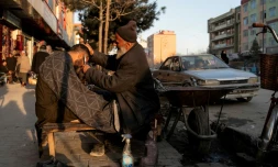 Un barbier coupe les cheveux d'un client dans une rue de Kaboul le 11 février 2026