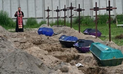 Le prêtre orthodoxe Andriy Golovin récite une prière sur les tombes de civils non identifiés, lors de leurs funérailles dans un cimetière de la ville de Boutcha, dans la région de Kyiv, le 11 août 2022