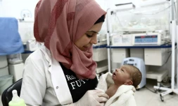 L'infirmière de 31 ans Malaké Harbaliyya tient dans ses bras un enfant à "l'hôpital de l'Espoir" dans le village rebelle d'Al-Ghandoura, dans la province d'Alep (nord), le 1er août 2018