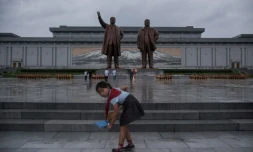 Une écolière nettoie le parvis devant les statues des leaders nord-coréens Kim Il-Sung (g) et Kim Jong-Il (d), le 27 juillet 2017 à Pyongyang