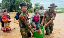 Des militaires aident les habitants à traverser les eaux à Pyinmana, dans la région de Naypyidaw en Birmanie, le 13 septembre 2024, à la suite de fortes pluies consécutives au typhon Yagi