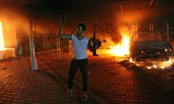 Un homme armé agite son fusil alors que des bâtiments et des voitures sont en flammes après avoir été incendiés à l'intérieur de l'enceinte du consulat américain à Benghazi, en Libye le 11 septembre 2012