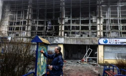 L'artiste français  Christian Guémy, alias C215, peint une de ses oeuvres sur un panneau près d'une station de métro et d'un marché alimentaire gravement endommagés par les frappes russes sur Kiev, le 1er avril 2022