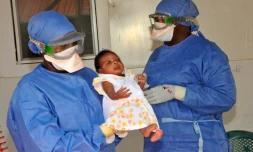 La petite Noubia dans les bras d'une soignante le 28 novembre 2015 à Conakry quelques jours après avoir été déclarée guérie du virus Ebola