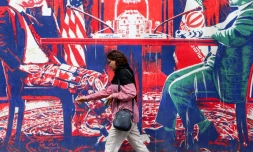 Une personne passe devant une fresque sur l'ancienne ambassade américaine à Téhéran, le 8 avril 2025 