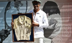 Yannick pose avec le maillot qu'il portait lors de sa victoire à Roland-Garros en 1983, devant une fresque inaugurée en son honneur, le 28 mai 2023