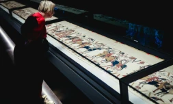 Une femme se penche pour observer la Tapisserie de Bayeux lors d'une avant-première réservée à la presse, organisée en amont de l'inauguration officielle au British Museum, dans le centre de Londres, le 7 septembre 2026