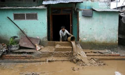 Un homme nettoie la boue devant sa maison, dans une zone touchée par les inondations à Katmandou, le 29 septembre 2024