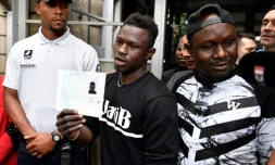 Mamoudou Gassama montre le récépissé régularisant sa situation à la sortie de la préfecture de Bobigny, mardi 29 mai 2018