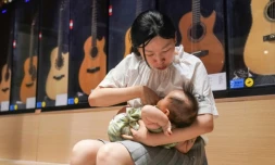 Dans cette photo prise le 5 août 2020, Wang Chao allaite son bébé dans son magasin de guitares à Shanghai