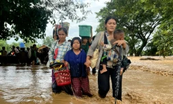 Des habitants marchent dans les eaux à Pyinmana, dans la région de Naypyidaw en Birmanie, le 13 septembre 2024, à la suite de fortes pluies consécutives au typhon Yagi