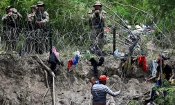 Des migrants ayant franchi le Rio Grande, qui marque la frontière entre le Mexique et les Etats-Unis, face aux barbelés et à la garde nationale américaine, le 11 mai 2023 à Brownsville, au Texas
