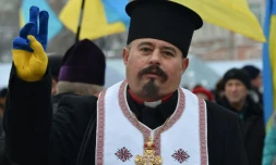 Un prêtre ganté aux couleurs de l'Ukraine fait le V de la victoire en arrivant devant la cathédrale Sainte-Sophie à KIev où va se dérouler un concile pour créer une Eglise ukrainienne indépendante, le 15 décembre 2018