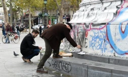 Des personnes posent des fleurs et des bougies face au monument de la Place de la République, le 14 novembre 2015 à Paris 