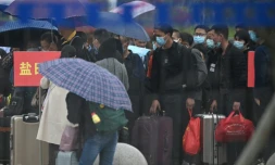 Des personnes portant un masque de protection font la queue pour acheter un billet de train à la gare de Macheng, le 25 mars 2020 dans la province chinoise du Hubei