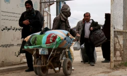 Des ressortissants afghans arrivent avec leurs effets personnels au poste-frontière d’Islam Qala, entre l’Afghanistan et l’Iran, dans la province de Herat Province, le 10 mars 2026, après leur arrivée en provenance d’Iran dans le contexte de la guerre au Moyen-Orient.