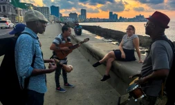 Des musiciens cubains chantent un boléro devant une femme assise sur le Malecon de La Havane, le 4 décembre 2023