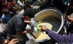 Des enfants palestiniens tentent de prendre ce qui reste dans un récipient de soupe aux lentilles dans un point de distribution de nourriture dans la ville de Gaza, le 25 juillet 2025