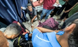 Des Palestiniens entourent l'une des personnes blessées en attendant de l'aide humanitaire près du point de passage de Zikim, dans le nord de la bande de Gaza, le 30 juillet 2025