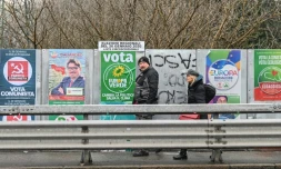 Des passants marchent devant des panneaux électoraux le 19 janvier 2020 à Bologne, avant les élections régionales en Emilie-Romagne (Italie)