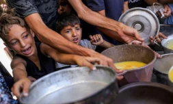 Des enfants palestiniens font la queue pour recevoir des repas d'une  organisation caritative locale à Gaza-ville, le 14 juillet 2025