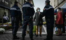 Une femme portant un masque de protection discute avec des gendarmes à l'entrée d'un marché à Libourne, le 30 octobre 2020 