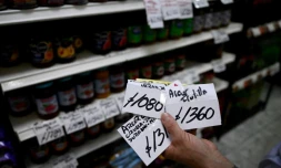Paola Basso, qui tient une supérette à Moron, dans la banlieue de Buenos Aires, montre des étiquettes d'anciens prix, le 22 novembre 2023