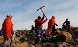 Une femme munie d'une pioche pour chercher ce qu'elle pense être des diamants, dans le village sud-africain de KwaHlathi le 15 juin 2021