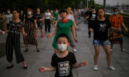 Des gens dansent dans la rue prÚs de la riviÚre Yangtsé à Wuhan (Chine) le 4 août 2020