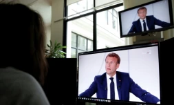 Une femme regarde une intervention télévisée du président français Emmanuel Macron le 14 juillet 2020 à Paris
