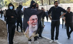 Des manifestants irakiens, dont l’un tient un portrait du guide suprême iranien assassiné, Ali Khamenei, se tiennent près de la Zone verte, où se trouve l’ambassade des États-Unis, à Bagdad, le 1er mars 2026.